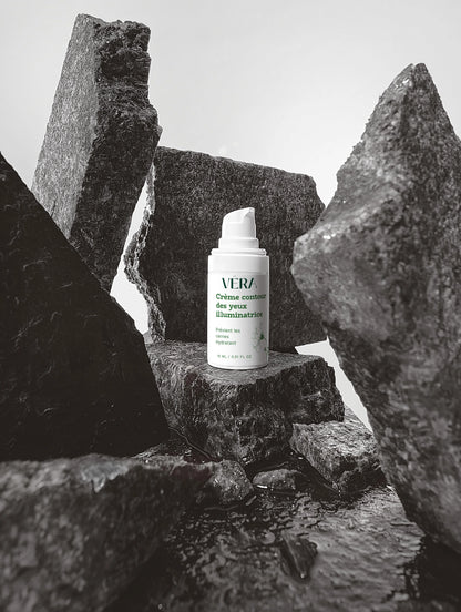 Crème contour des yeux illuminatrice VERA, soin hydratant regard, flacon posé sur décor minéral.