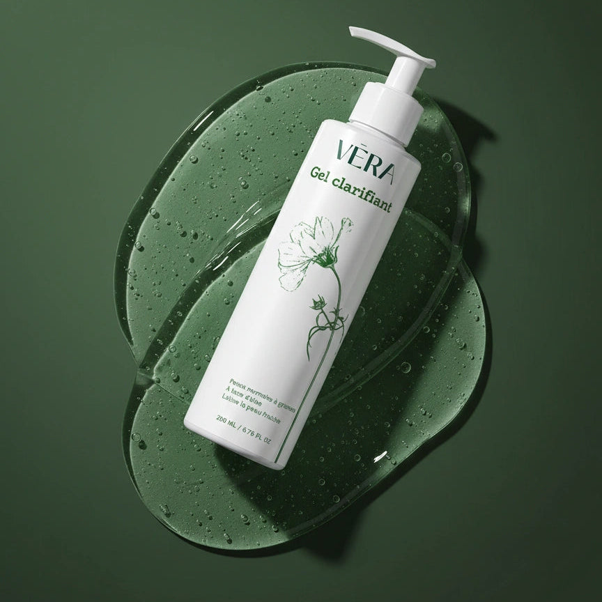 Flacon VERA Gel clarifiant incliné sur une texture de gel transparent avec bulles sur fond vert.