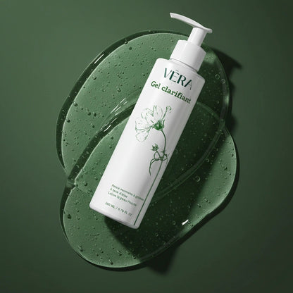 Flacon VERA Gel clarifiant incliné sur une texture de gel transparent avec bulles sur fond vert.