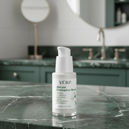 Flacon du sérum Collagène Boost VERA posé sur un plan de salle de bain en marbre vert, avec miroir en arrière-plan.
