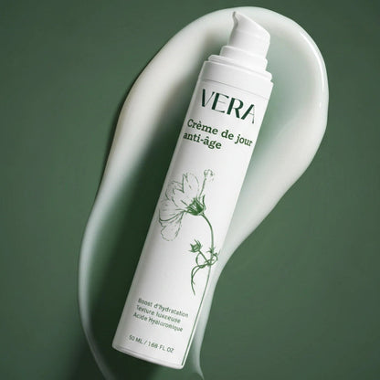 Crème de jour anti-âge VERA en flacon pompe, posée en diagonale sur une trace de crème.