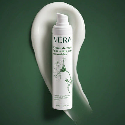 Flacon pompe de la crème de nuit barrière aux céramides VERA devant une trace de crème blanche sur fond vert.