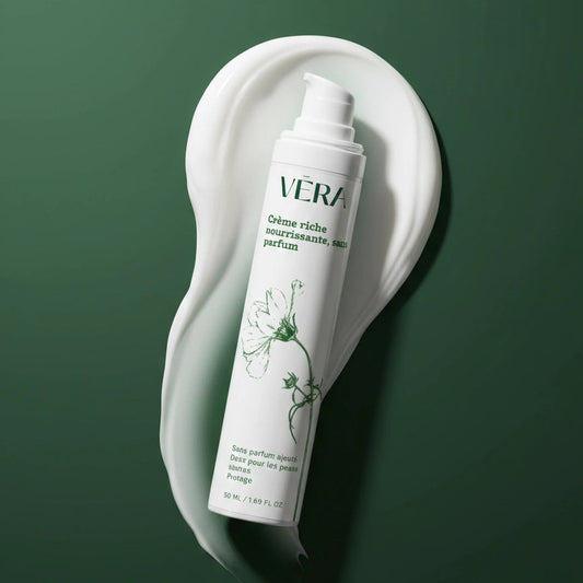 Flacon VERA crème riche nourrissante sans parfum incliné sur une noisette de crème blanche sur fond vert.