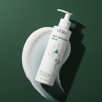 Flacon VERA Lait nettoyant doux 190 ml posé sur une texture de lait cosmétique blanc sur fond vert.
