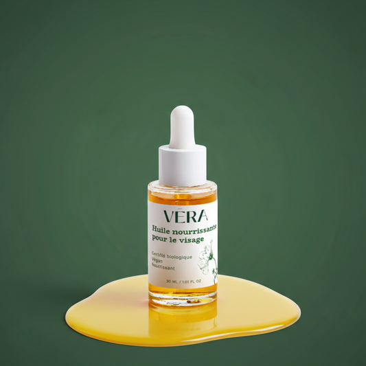 Flacon compte-gouttes VERA Huile nourrissante pour le visage posé dans une flaque d’huile dorée sur fond vert.
